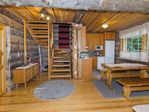 Een landelijk vakantiehuisje met een houten trap, een keuken met een magnetron en een eettafel.