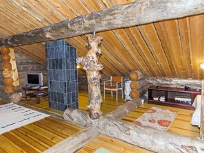 A rustic interior with wooden beams, a stone wall, a television, and a bookshelf. - Köllölä 3 by Interhome (Nunnanlahti)