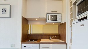 Een kleine keuken met een magnetron, spoelbak en vaatwasser.