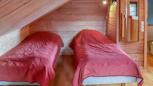 A small, cozy room with two single beds, wooden walls, and a sloped ceiling. - Villa hytönen 1 by Interhome (Äkäslompolo)