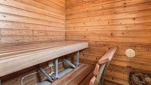 A sauna room with wooden walls, a bench, a bench seat, a green bucket, and a trash can. - Tammukka i by Interhome (Äkäslompolo)