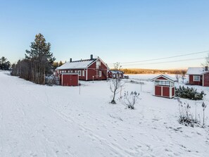 A rural landscape with a snow-covered field, a red barn, and a small wooden structure. - Tammukka i by Interhome (Äkäslompolo)