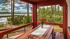 A wooden deck with a table and bench, overlooking a lake and forest. - Kallioniemi by Interhome (Kiuruvesi)