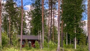 A cabin surrounded by tall trees and a pond with water lilies. - Kallioniemi by Interhome (Kiuruvesi)