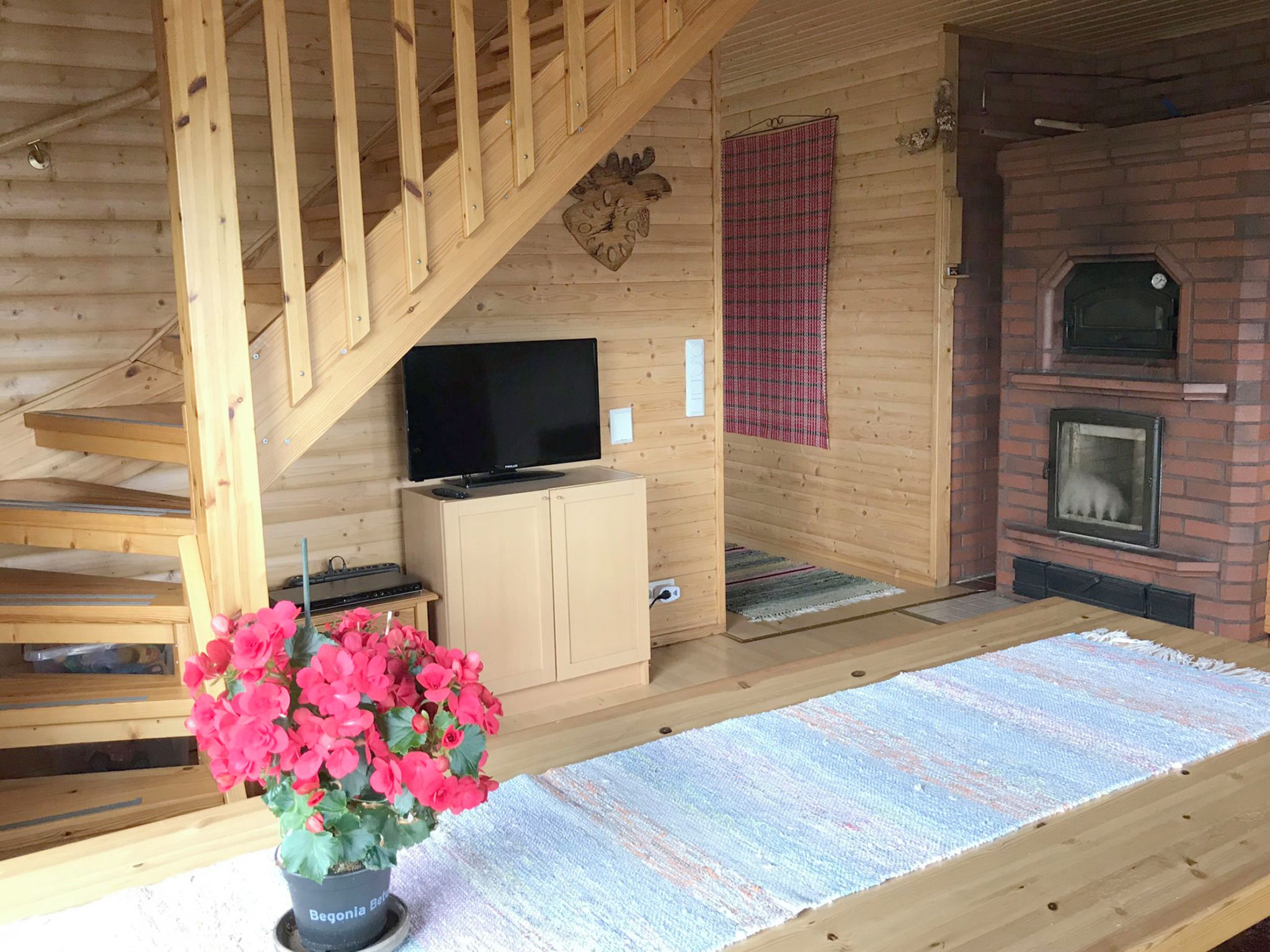 Een houten interieur met een televisie, open haard en trap.