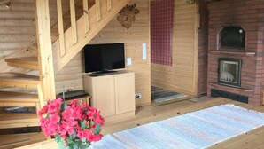A wooden interior with a TV, fireplace, and staircase. - Kallioniemi by Interhome (Kiuruvesi)