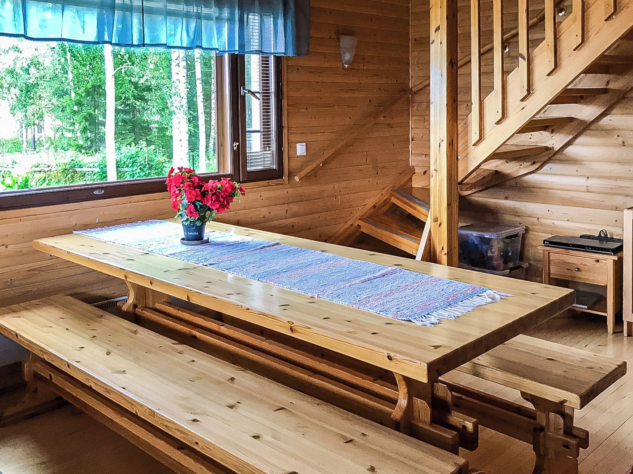 Un interior de madera con una mesa, bancos y una escalera.