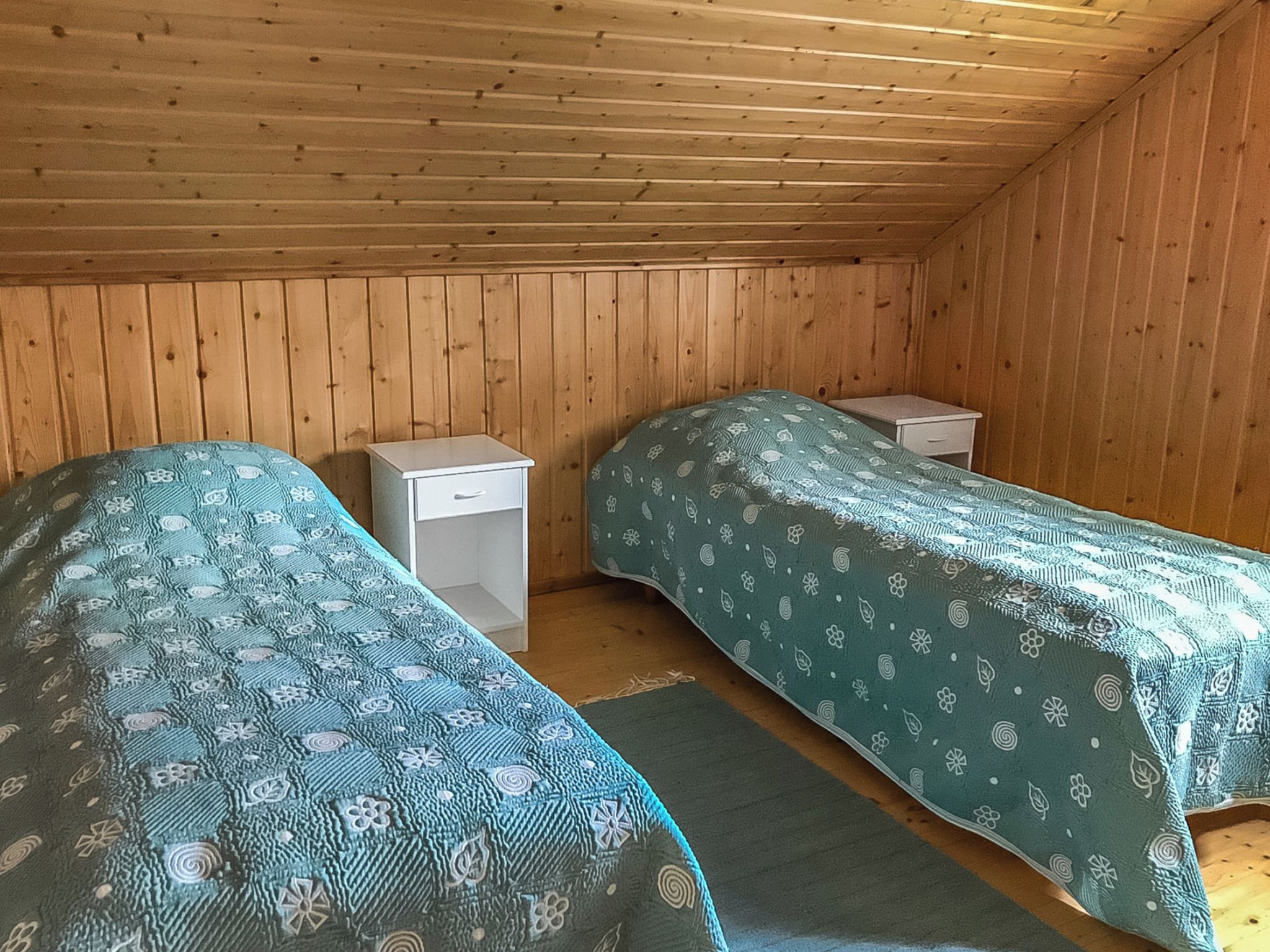 A room with two single beds, each with a matching headboard and footboard, and a small bedside table.