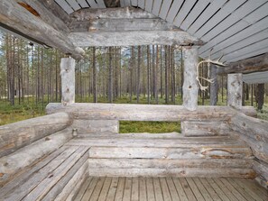Una cabana de fusta rústica amb un espai central obert, envoltada per un bosc.