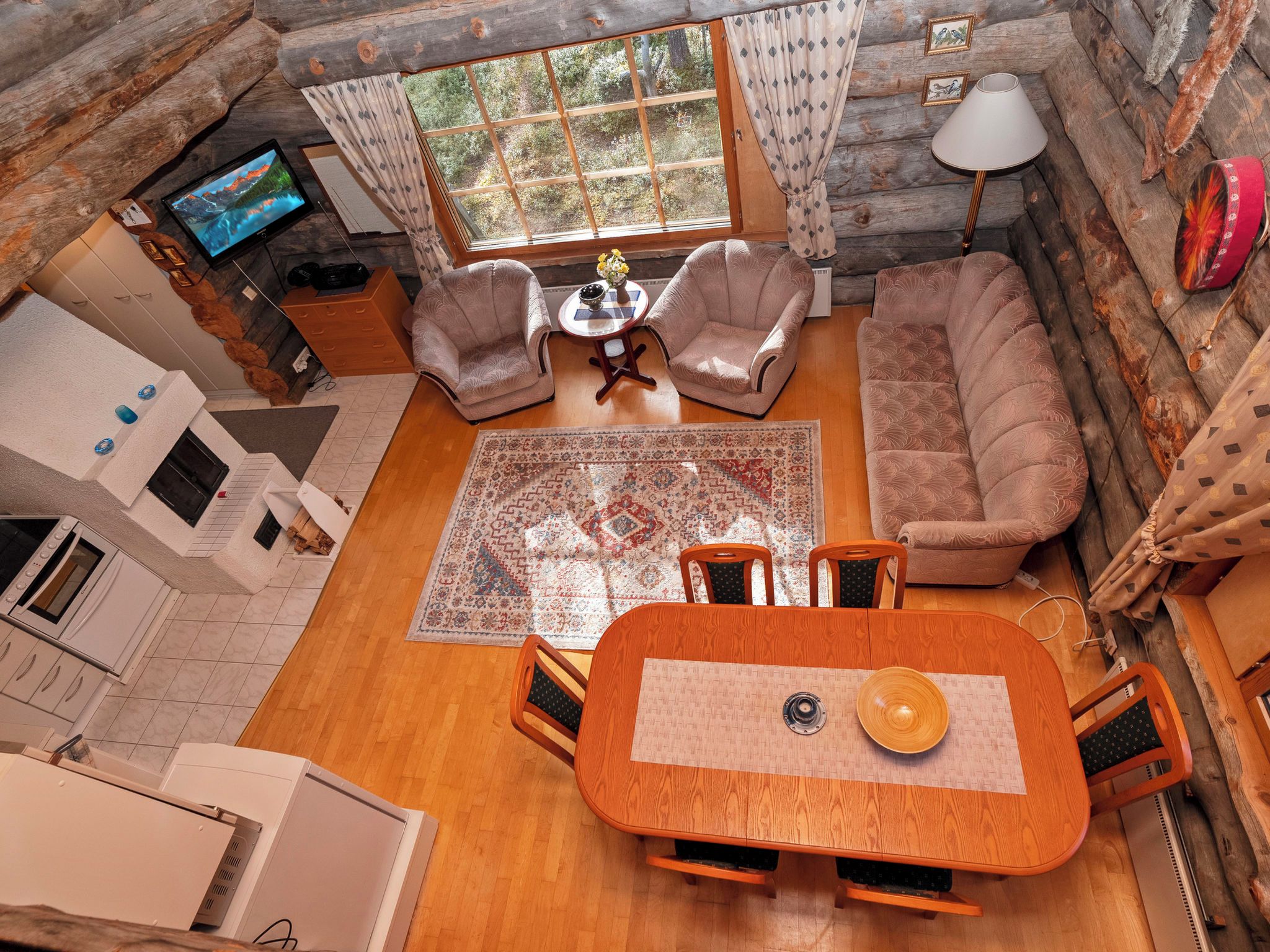 L'intérieur d'une cabane en rondins, avec un coin repas, un canapé et un téléviseur.