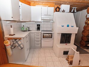 A compact kitchen with white cabinets, a built-in oven, a coffee maker, and a small sink. - Rukanlumous 1 by Interhome (Kuusamo)