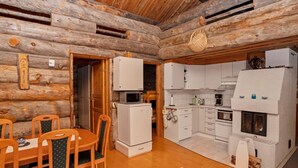A log cabin interior with a dining area, kitchen, and a fireplace. - Rukanlumous 1 by Interhome (Kuusamo)