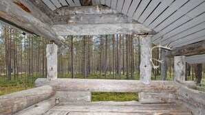 A rustic wooden cabin with a central seating area and a view of a forest. - Rukanlumous 1 by Interhome (Kuusamo)