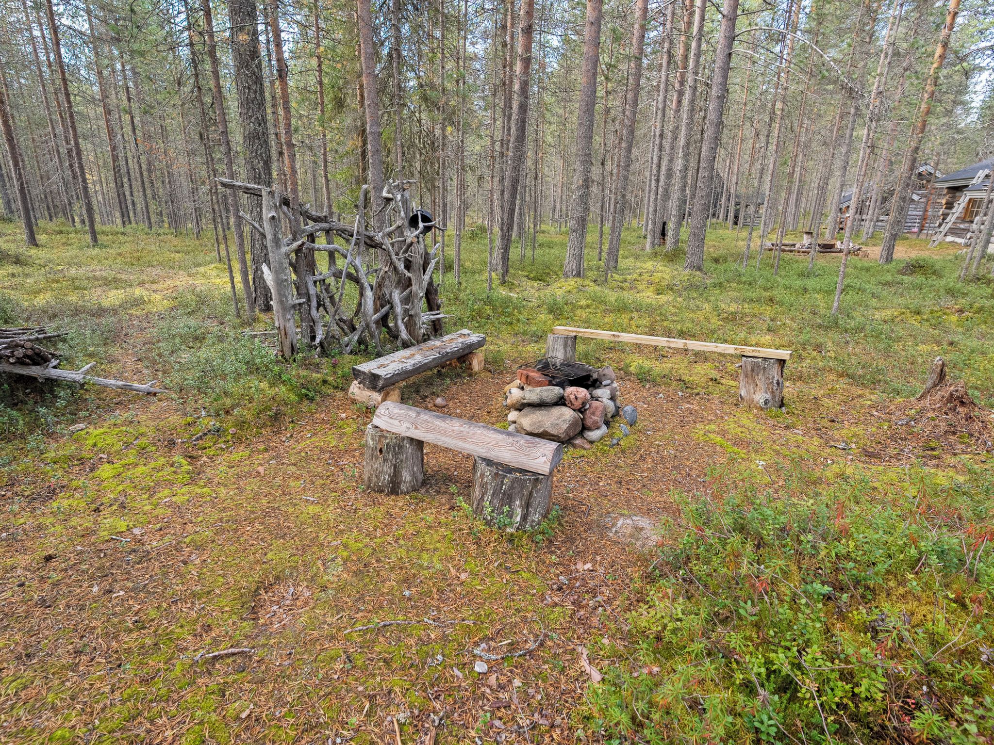 Un espace extérieur rustique avec un banc en bois, un foyer et un tas de pierres.