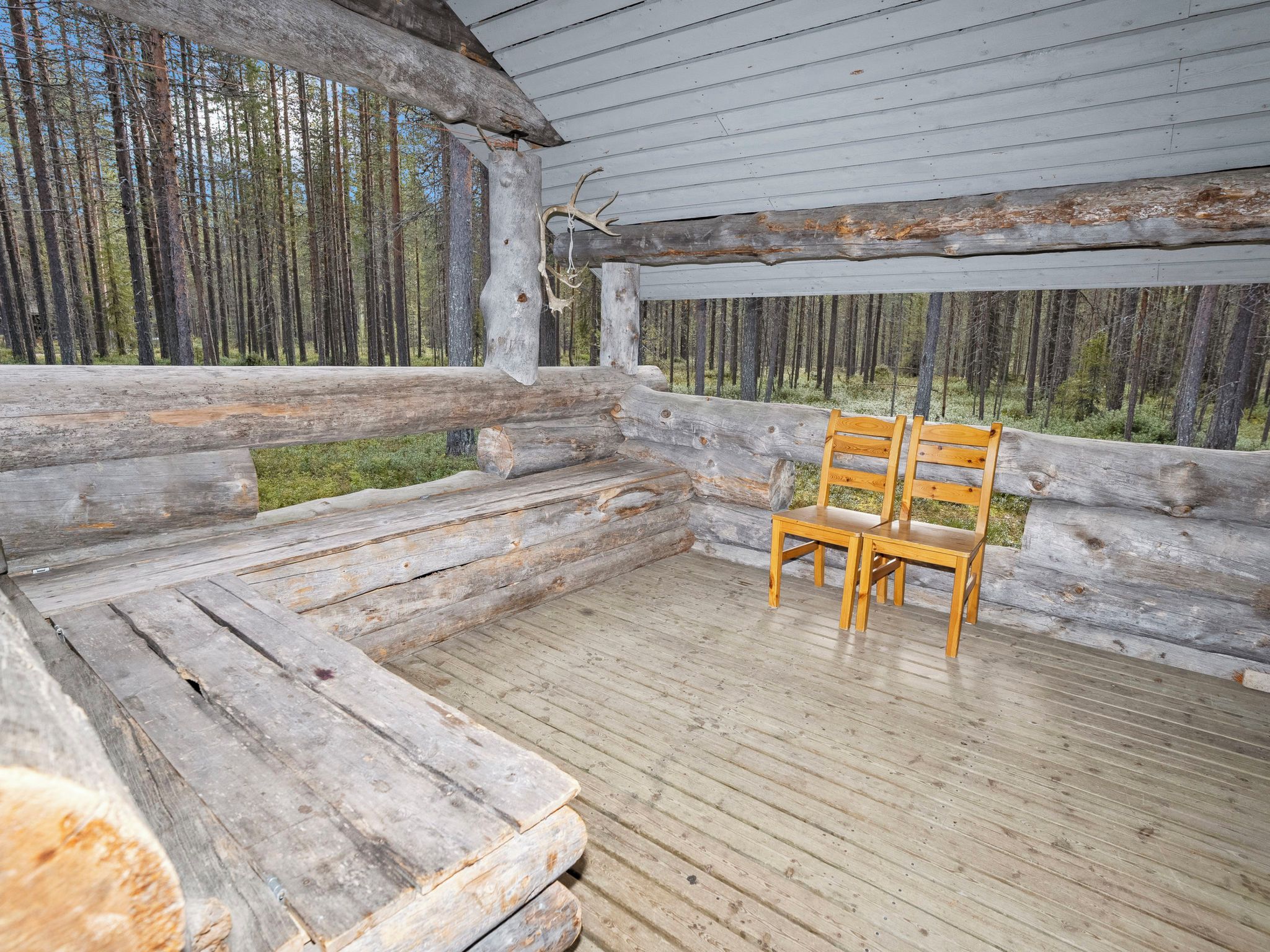 Hirsimökki, jossa on puinen terassi ja penkki.