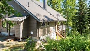 Eine Holzhütte mit geneigtem Dach, einer Veranda und einer Treppe, die zu einer Terrasse führt.