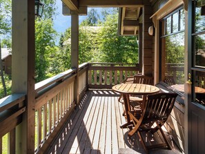 A wooden deck with a round table and chairs, surrounded by a railing, overlooking a forested area. - Kultakoto b by Interhome (Nilsiä)