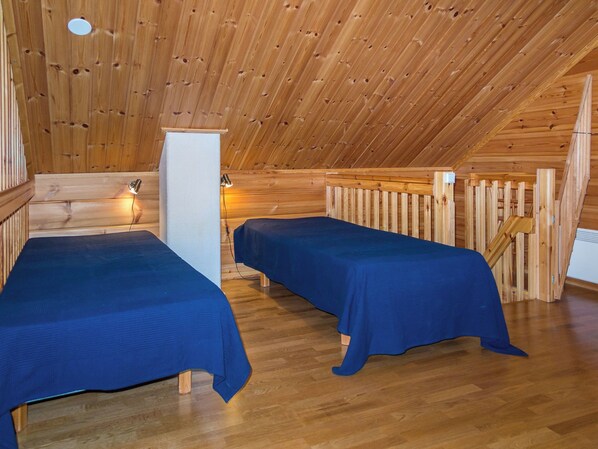 A wooden cabin with two beds, a wooden ceiling, and a small table.