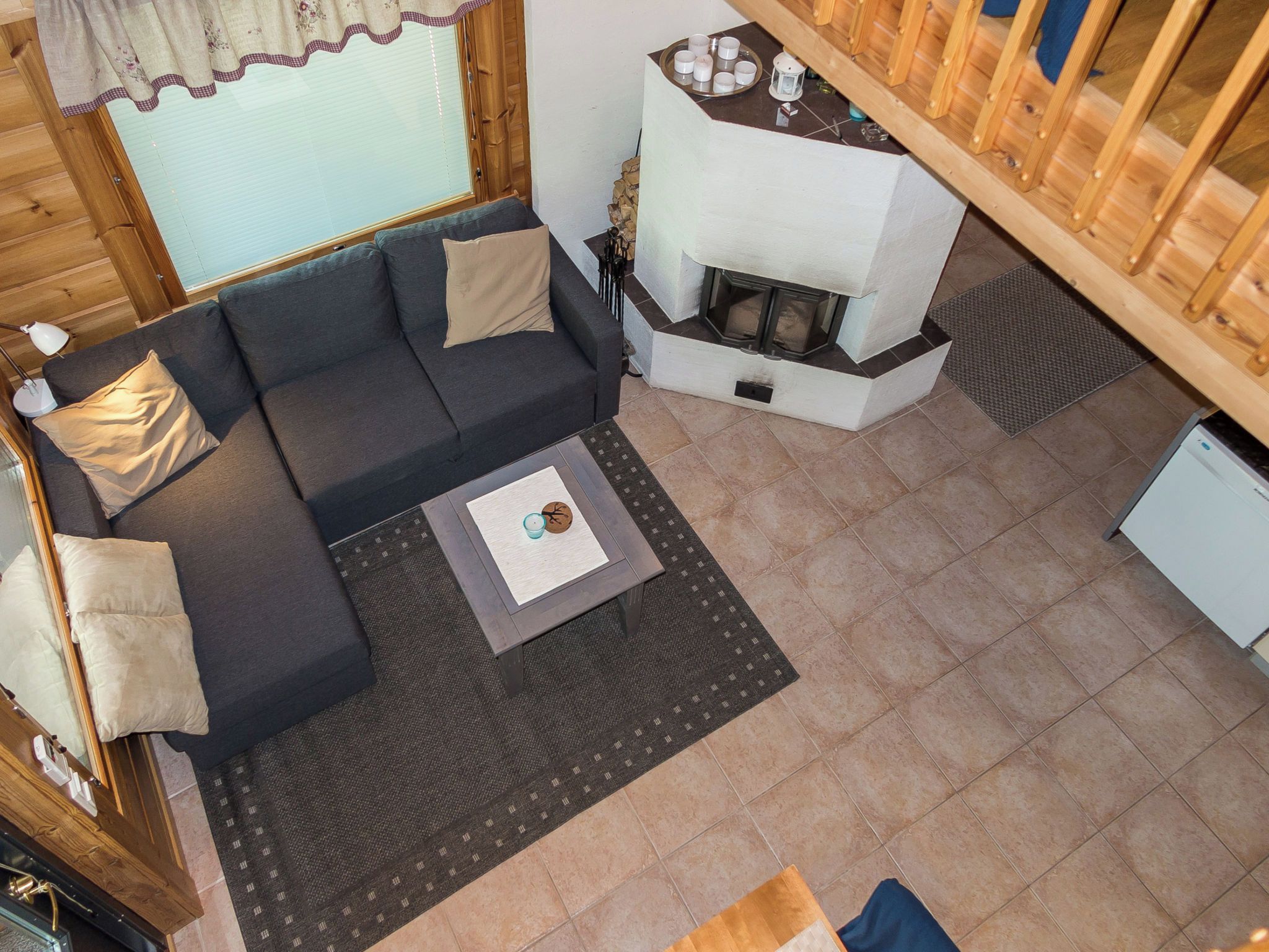 A cozy cabin interior with a sofa, a small table with a candle, and a fireplace.