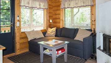 Ein gemütliches Blockhaus-Interieur mit einer Couch, einem kleinen Tisch und einem Kamin.