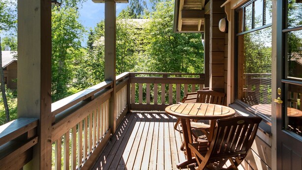 Eine Holzterrasse mit Tisch und Stühlen mit Blick auf ein bewaldetes Gebiet.