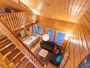 L'intérieur d'un chalet en bois comprend un coin repas, un canapé et un escalier.