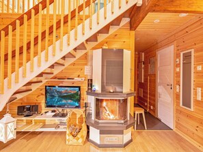 A wooden interior with a staircase, a fireplace, a television, and a small table with items on it. - Kevätpiippo b by Interhome (Ylläsjärvi)
