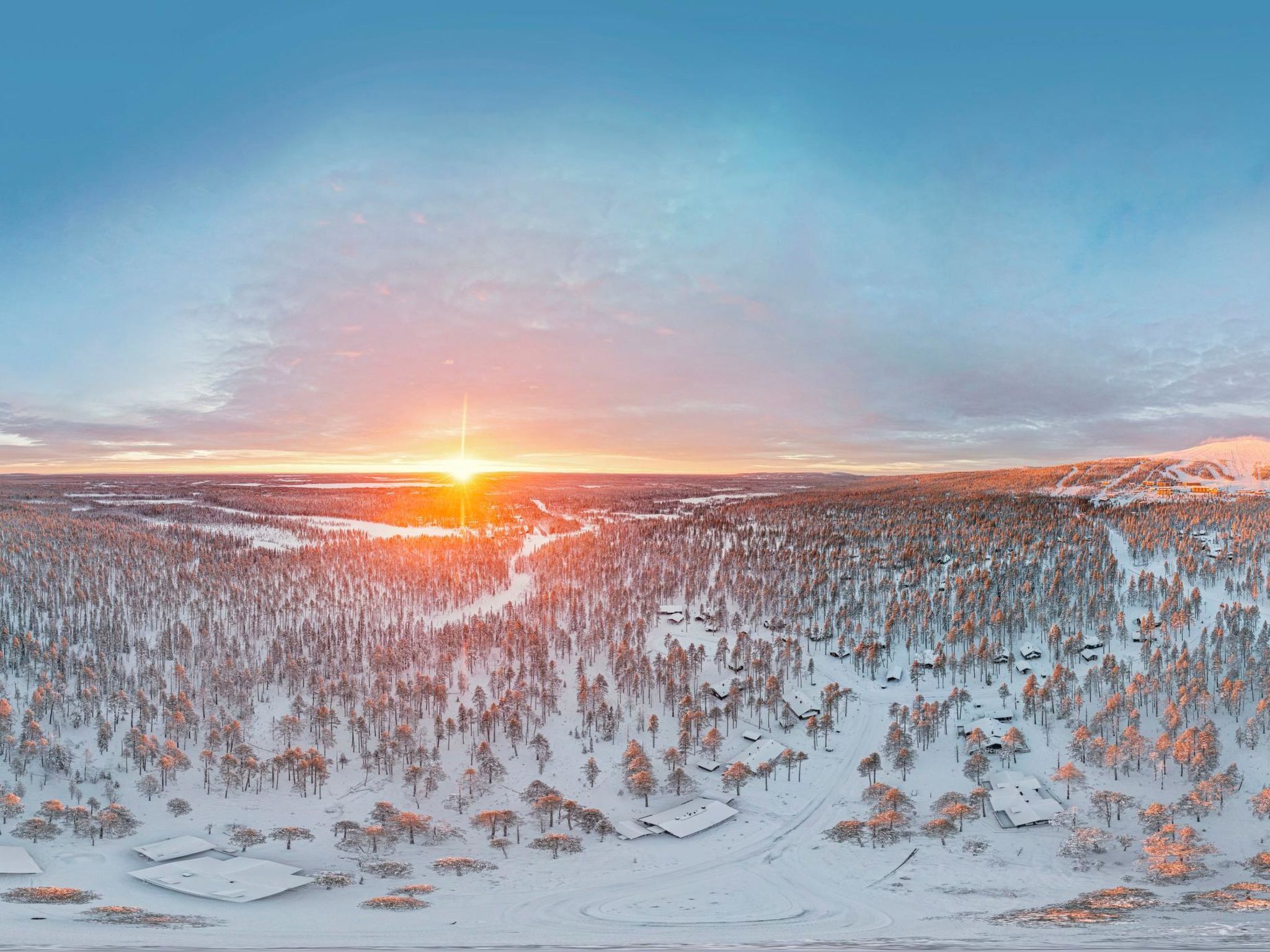 Un vaste paysage boisé, avec un ciel dégagé et un soleil couchant.