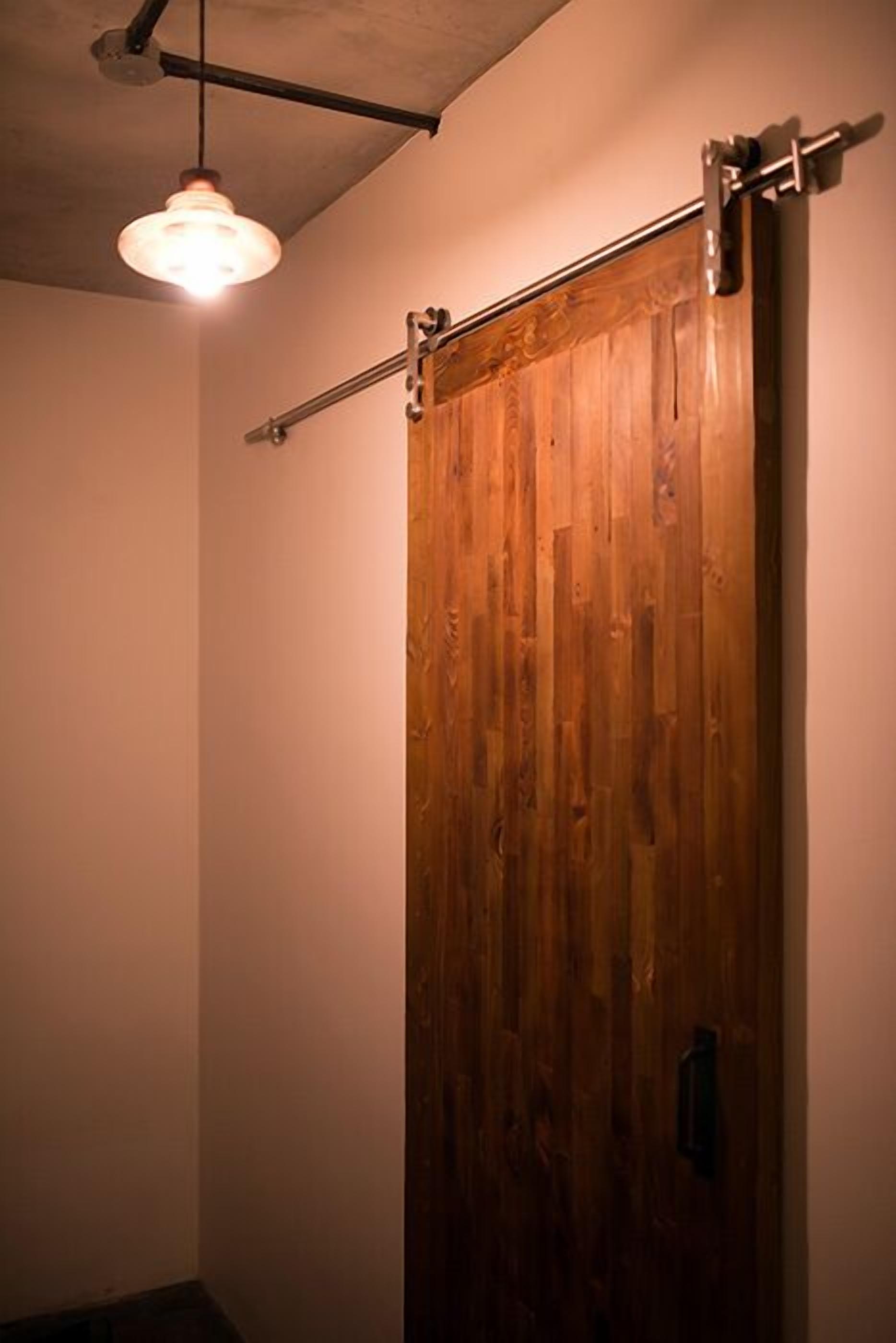 Une porte coulissante en bois, dotée d’un rail métallique et d’un luminaire suspendu.
