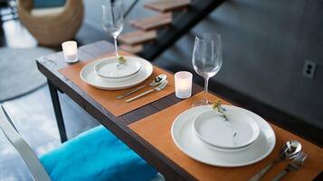 A dining table set with plates, cutlery, and glasses, with a candle and a vase of flowers.