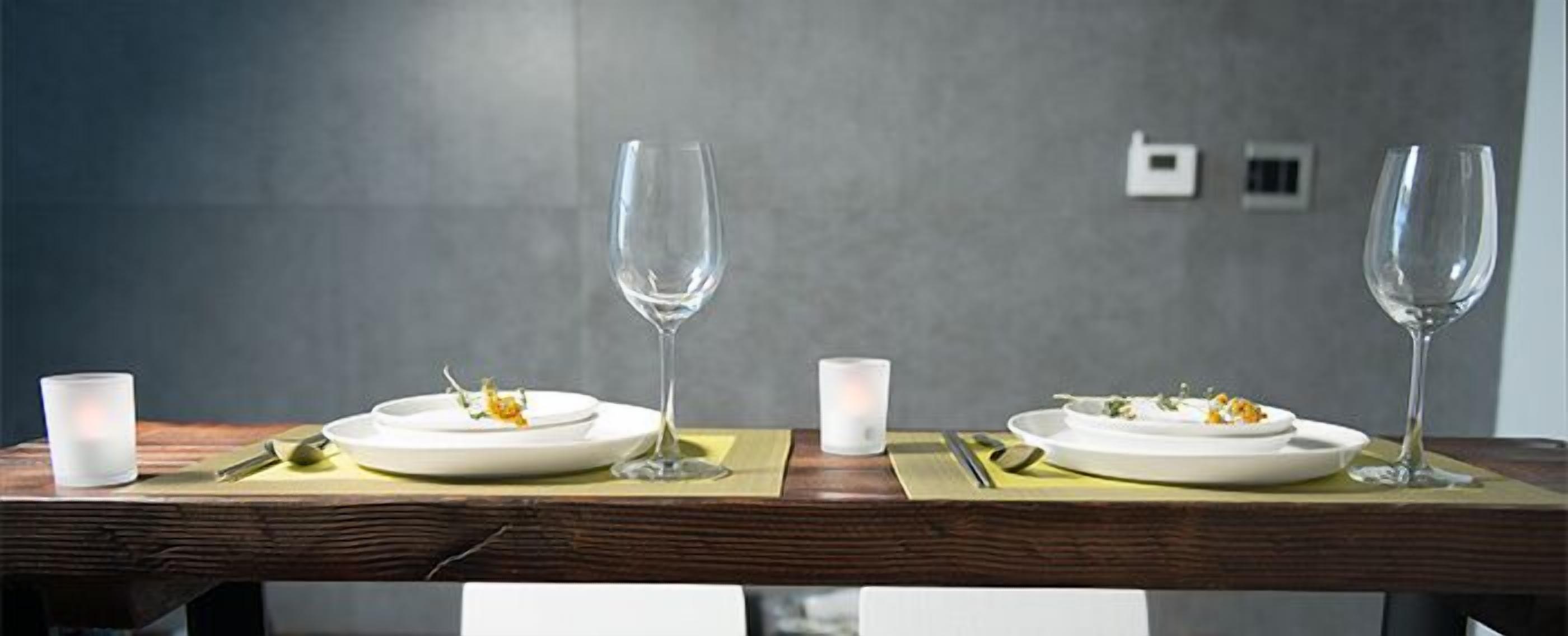 Una mesa de comedor con dos platos de comida, dos copas de vino y dos velas.