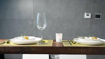 Una mesa de comedor con dos platos de comida, dos copas de vino y dos velas.