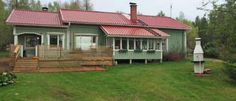 Ett envåningshus med ett rött tegeltak, en veranda med ett räcke och en skorsten.