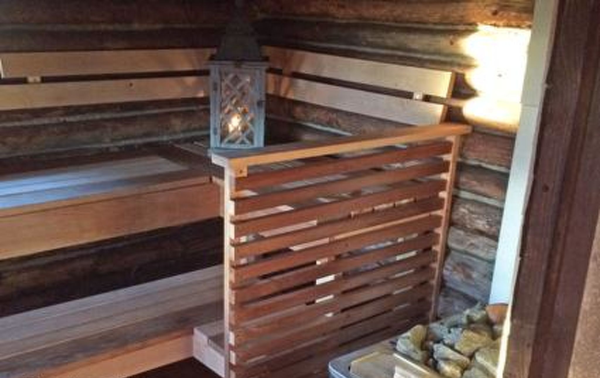 A wooden sauna with a stone wall and a metal container labeled "NATURAL".