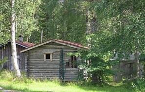 Un chalet rustique en bois, avec un toit rouge, entouré d’une végétation luxuriante.