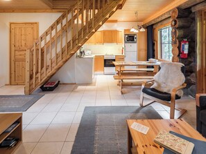 A wooden interior with a staircase, a kitchen area, and a seating area with a fireplace.