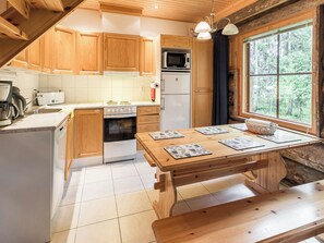 A kitchen with wooden cabinets, a stove, a microwave, and a dining table with placemats.