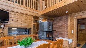 L’intérieur d’un chalet en bois comprend un coin repas, une cuisine et une cheminée.