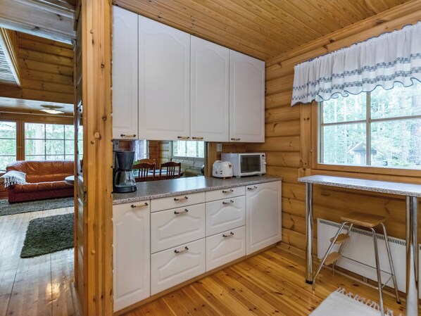 A compact kitchen with white cabinets, a microwave, and a small table.