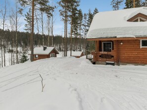 Een chalet met een houten gevel en een sneeuwwitte dak, omgeven door een bos.