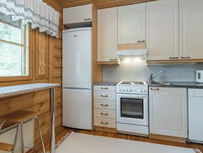 Een kleine keuken met een koelkast, fornuis, oven en spoelbak.