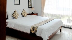 Un dormitorio con una cama grande, una mesita de noche, una lámpara y dos cuadros en la pared.