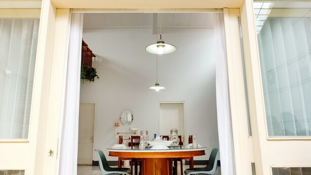 Un comedor con una mesa redonda, sillas e iluminación colgante.