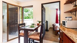 A dining area with a table set for two, a microwave, and a sliding glass door leading to a balcony.