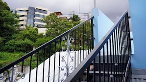 A staircase with black railings and a decorative balustrade, leading to a building with a blue exterior.