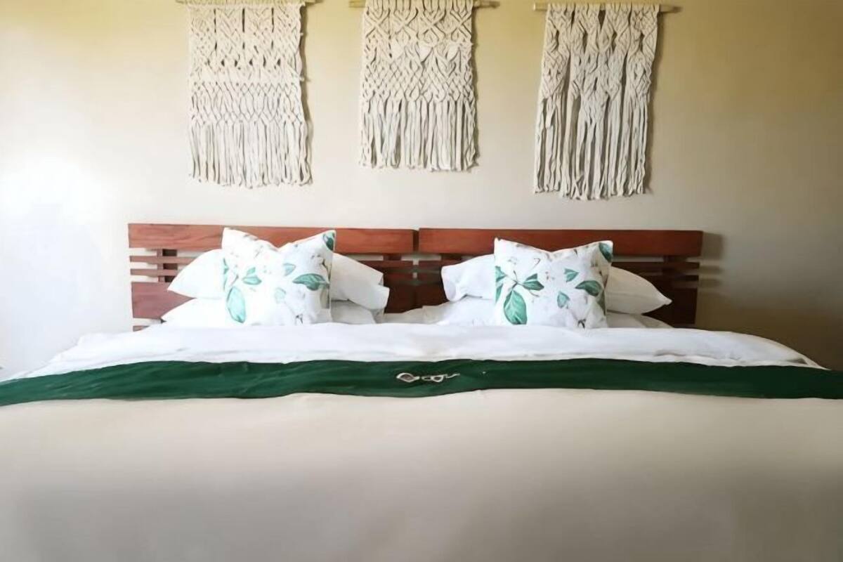 Una cama con cabecera de madera, ropa de cama blanca y manta verde.