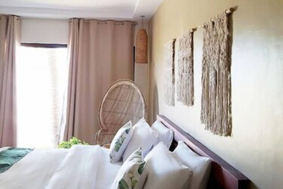 Una habitación de hotel con cama, cortinas, una silla y decoración en la pared.