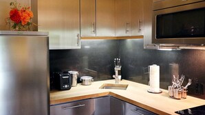 Une cuisine moderne dotée d’appareils électroménagers en acier inoxydable, d’un plan de travail en bois et d’un four à micro-ondes encastré.