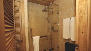 Une salle de bain moderne dotée d’une douche à parois de verre, de lambris en bois et de toilettes noires.