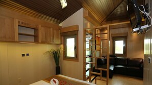 Une chambre d’hôtel avec un lit, un plafond en bois, une télévision, un canapé et une plante.